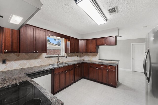 kitchen featuring dark stone counters, sink, stainless steel appliances, and a textured ceiling