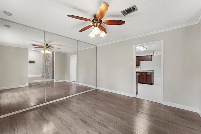 unfurnished bedroom with ceiling fan, dark hardwood / wood-style floors, ornamental molding, and a closet