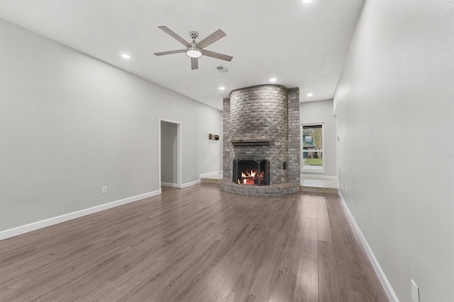 unfurnished living room with hardwood / wood-style flooring, ceiling fan, and a fireplace