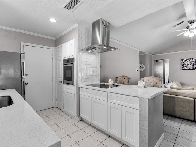 kitchen with light tile patterned floors, white cabinets, wall chimney range hood, and appliances with stainless steel finishes