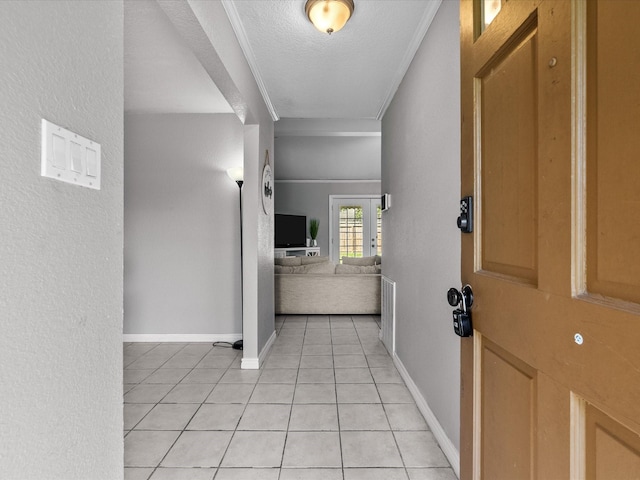 corridor with light tile patterned flooring, ornamental molding, and a textured ceiling