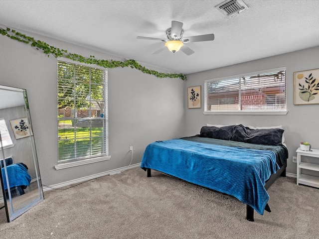 bedroom featuring multiple windows, ceiling fan, carpet, and a textured ceiling