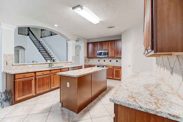 kitchen featuring a center island, sink, a textured ceiling, kitchen peninsula, and stainless steel appliances