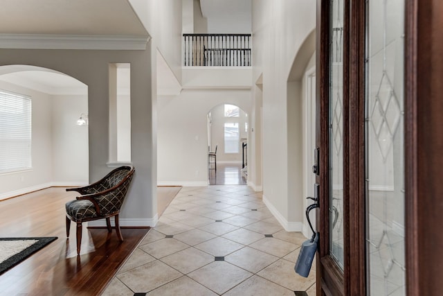 entrance foyer with ornamental molding, light wood-type flooring, a healthy amount of sunlight, and a notable chandelier