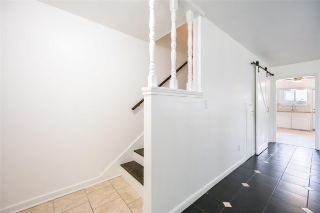 staircase featuring a barn door, ceiling fan, tile patterned flooring, and sink