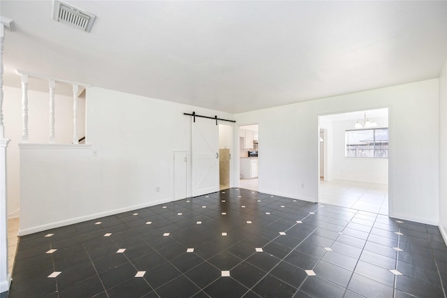 tiled empty room featuring a chandelier, a barn door, and washer / clothes dryer