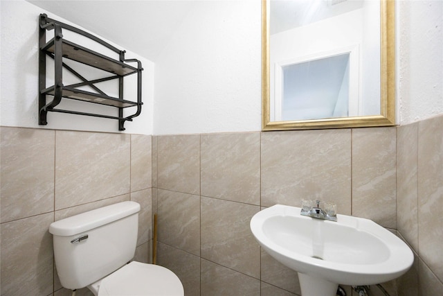 bathroom with sink, tile walls, and toilet