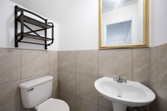 bathroom featuring sink, tile walls, and toilet