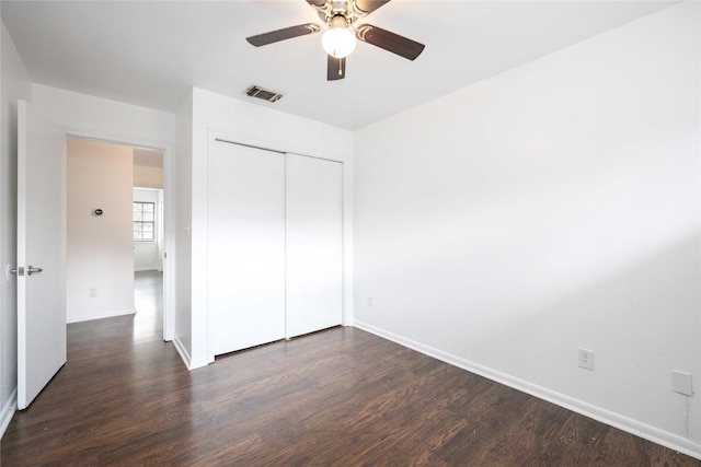 unfurnished bedroom with ceiling fan, dark hardwood / wood-style floors, and a closet