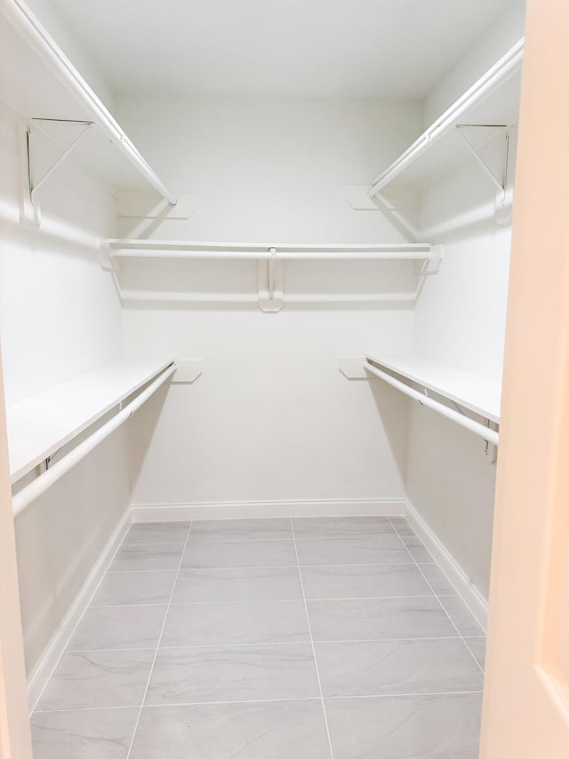 walk in closet with light tile patterned floors