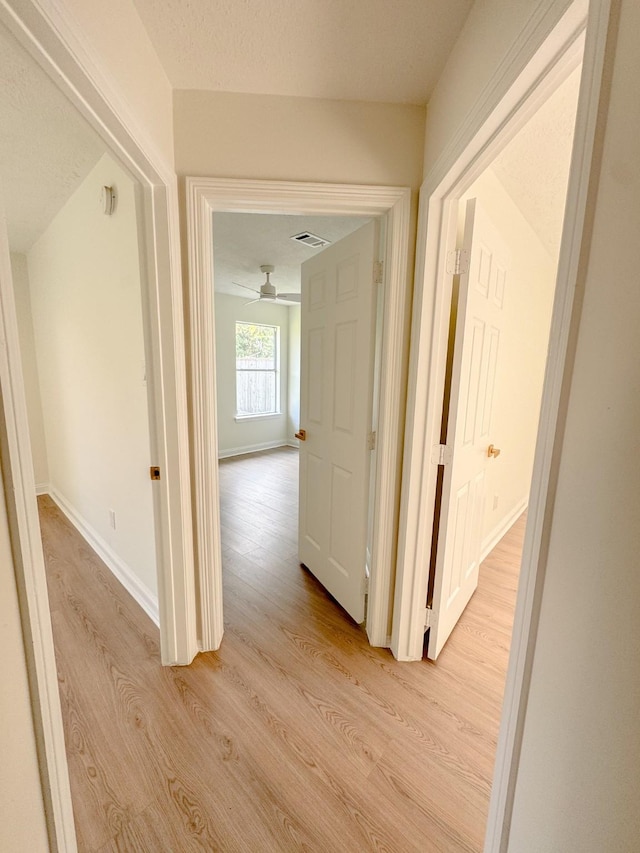 hall featuring light hardwood / wood-style floors and a textured ceiling