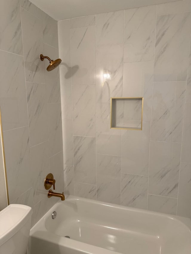 bathroom with tiled shower / bath combo and toilet