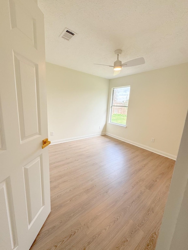 spare room with a textured ceiling, light hardwood / wood-style floors, and ceiling fan