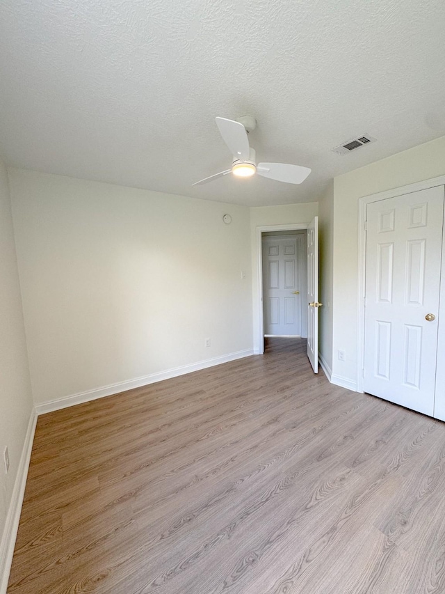 spare room with ceiling fan, light hardwood / wood-style floors, and a textured ceiling