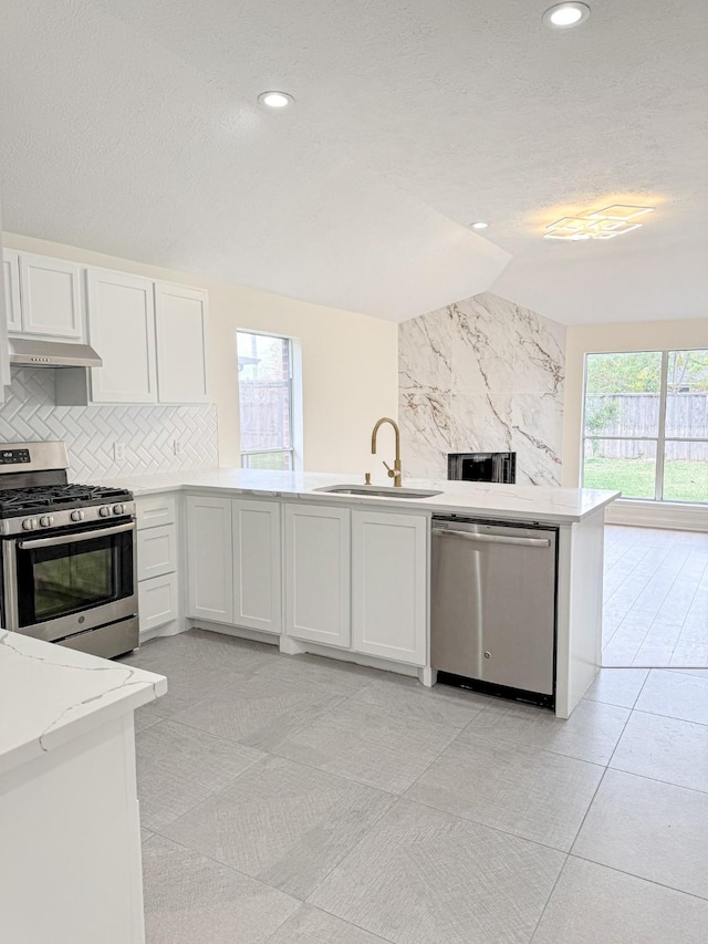 kitchen featuring sink, stainless steel appliances, light stone counters, backsplash, and white cabinets