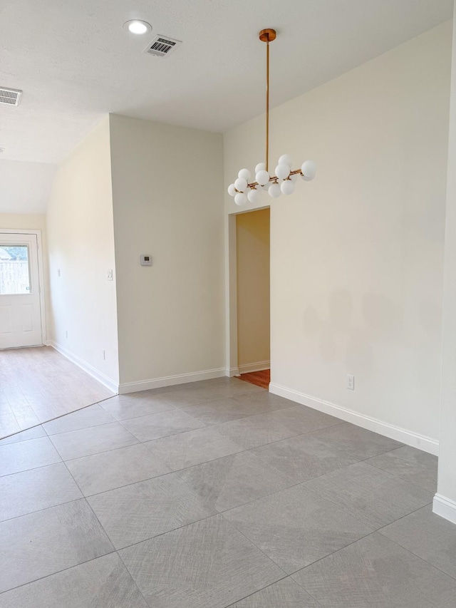 tiled spare room featuring vaulted ceiling and an inviting chandelier