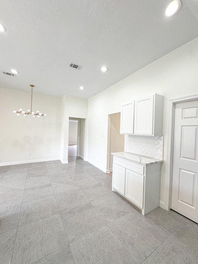 spare room featuring a textured ceiling and a notable chandelier