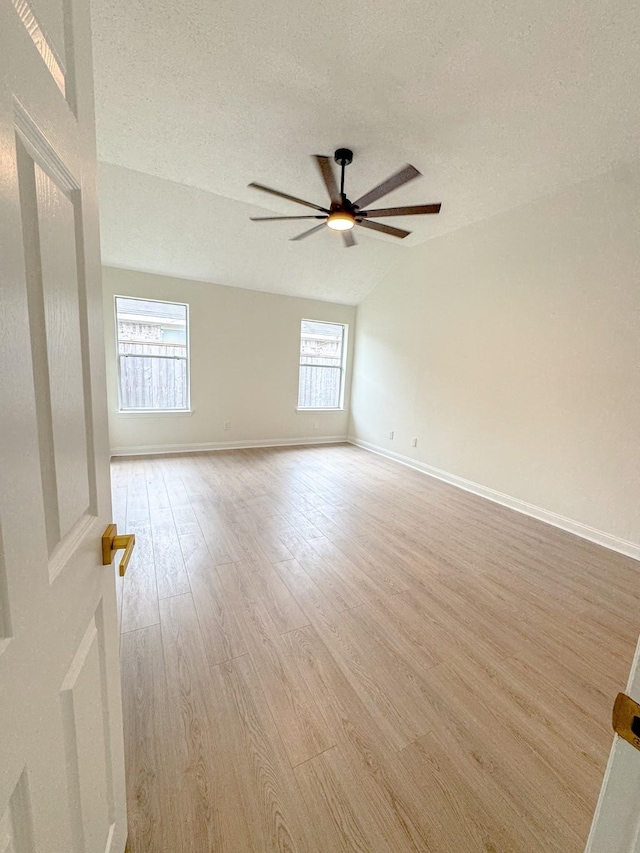 empty room with vaulted ceiling, a wealth of natural light, ceiling fan, and a textured ceiling