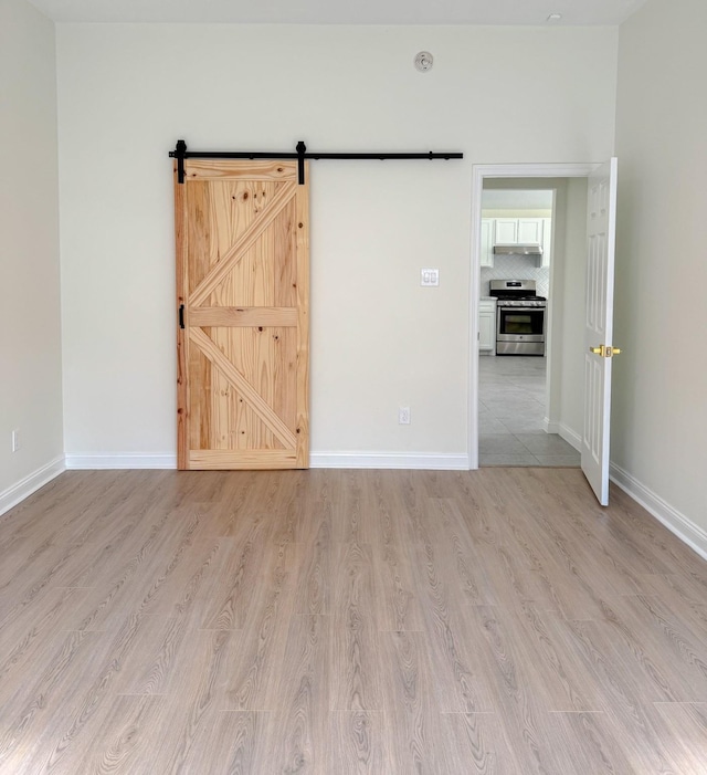 spare room featuring a barn door and light hardwood / wood-style floors