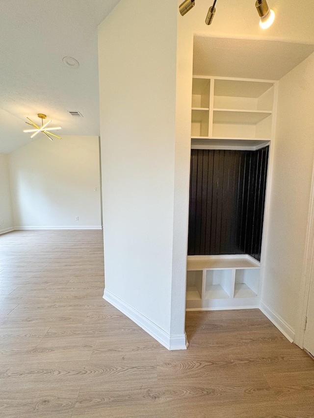 mudroom with built in shelves, light wood-type flooring, and lofted ceiling