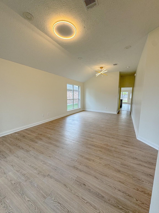 empty room featuring ceiling fan, light wood-type flooring, lofted ceiling, and a textured ceiling