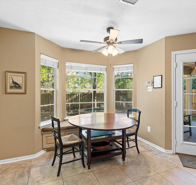 tiled dining area with ceiling fan and a textured ceiling