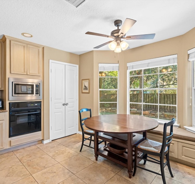 tiled dining space featuring ceiling fan and a textured ceiling