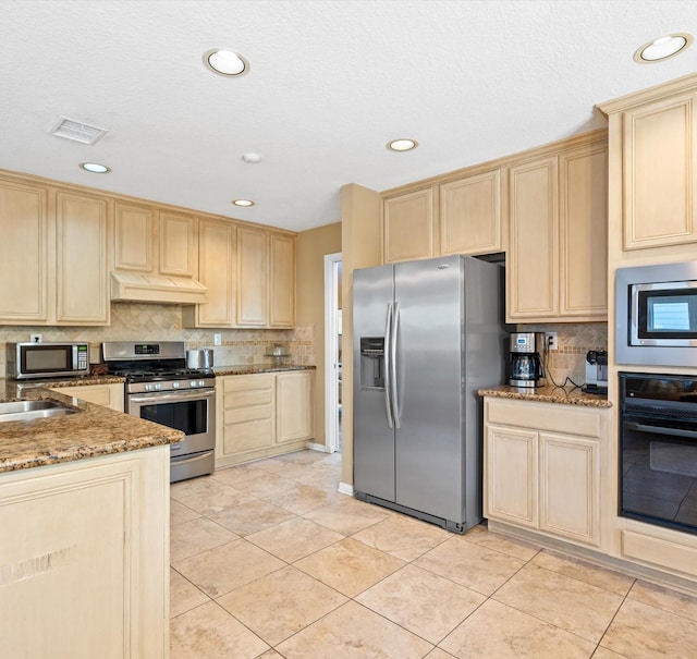 kitchen featuring appliances with stainless steel finishes, custom range hood, sink, stone counters, and light tile patterned flooring