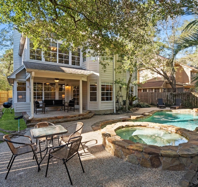 back of property with ceiling fan, a patio, and a pool with hot tub