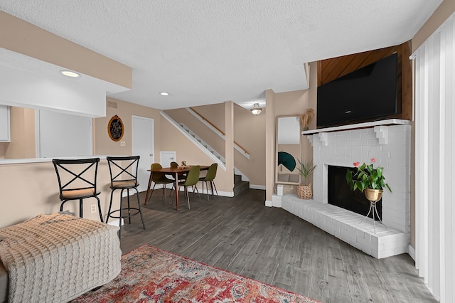 living room with a textured ceiling, a fireplace, and dark wood-type flooring