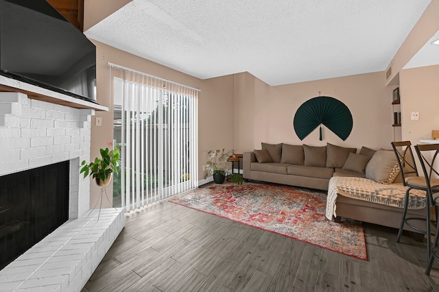 living room featuring a fireplace, wood-type flooring, and a textured ceiling