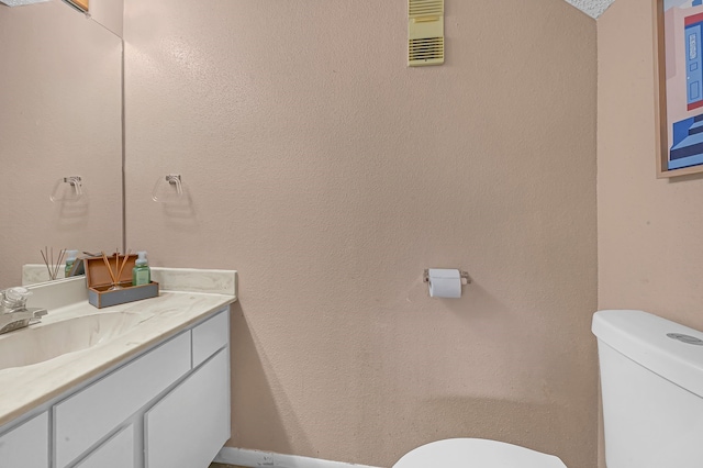 bathroom with vanity, toilet, and a textured ceiling