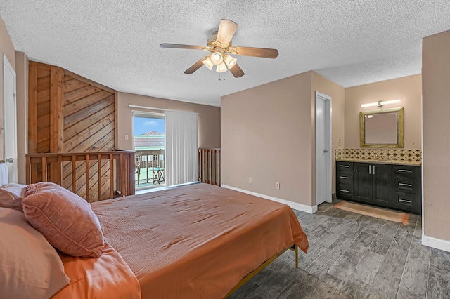 bedroom with dark wood-type flooring, ensuite bathroom, ceiling fan, access to exterior, and a textured ceiling