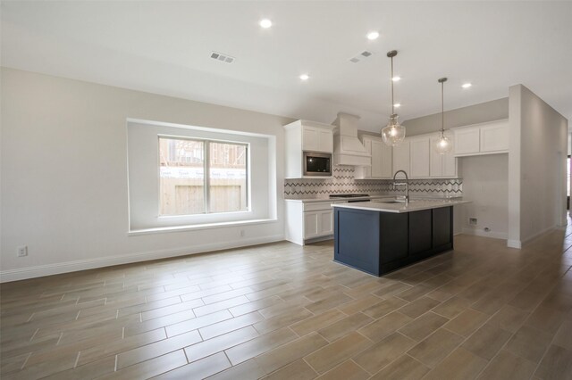 4030 Colony Ln, Missouri City, TX 77459 - kitchen with custom range hood, stainless steel microwave, white cabinets, a sink, and recessed lighting