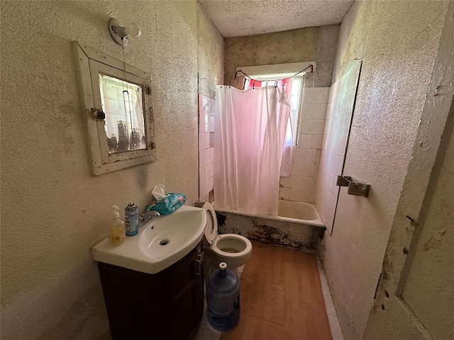 full bathroom featuring vanity, a textured ceiling, shower / tub combo with curtain, hardwood / wood-style floors, and toilet