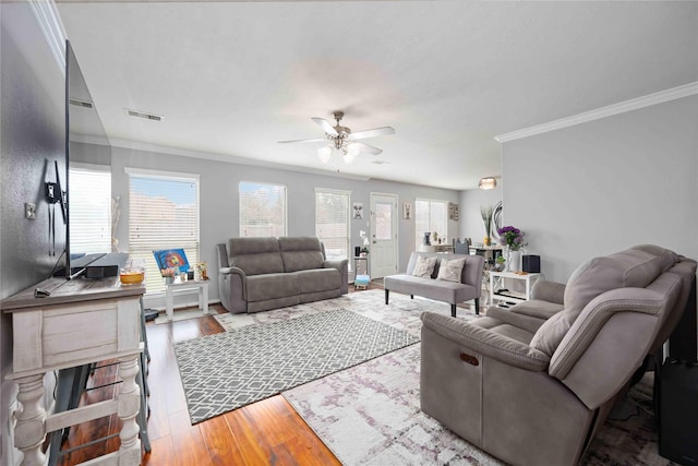 living room featuring hardwood / wood-style floors, ceiling fan, and crown molding