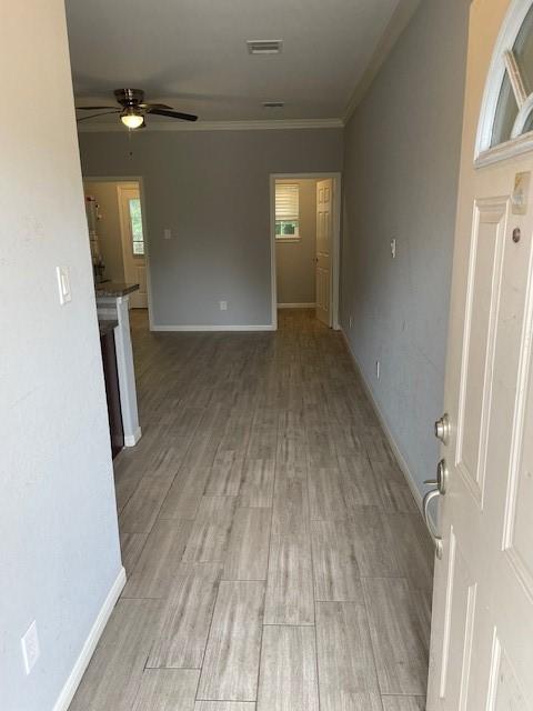 unfurnished living room featuring ceiling fan, light wood-type flooring, and ornamental molding