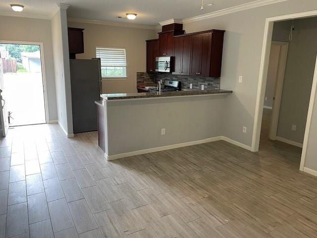 kitchen with a wealth of natural light, stainless steel range, backsplash, kitchen peninsula, and fridge