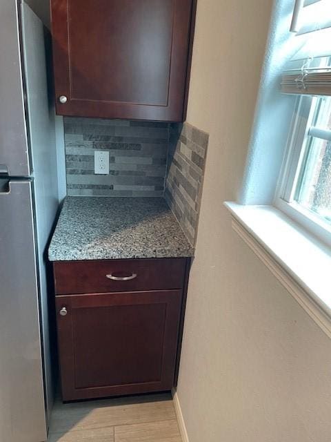 kitchen featuring decorative backsplash, stainless steel refrigerator, and light stone counters