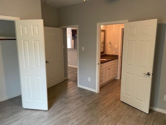 unfurnished bedroom featuring light wood-type flooring, connected bathroom, and a closet