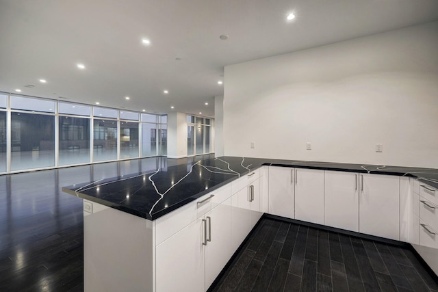 kitchen featuring kitchen peninsula, dark wood-type flooring, white cabinets, and floor to ceiling windows