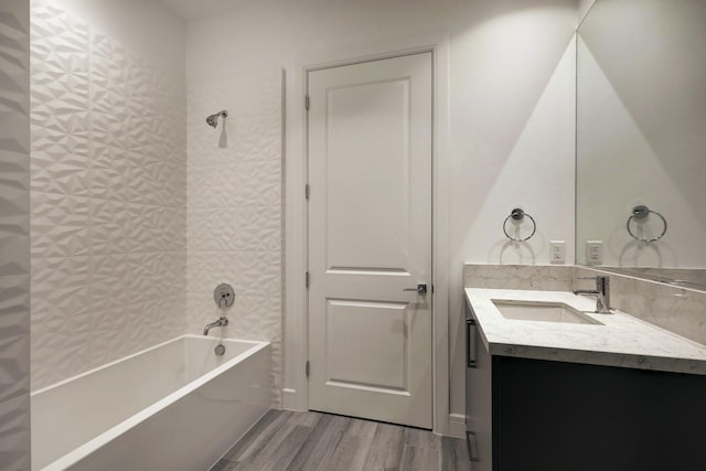 bathroom featuring hardwood / wood-style flooring, tiled shower / bath combo, and vanity