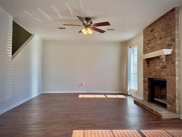 unfurnished living room with ceiling fan, dark hardwood / wood-style flooring, and a brick fireplace