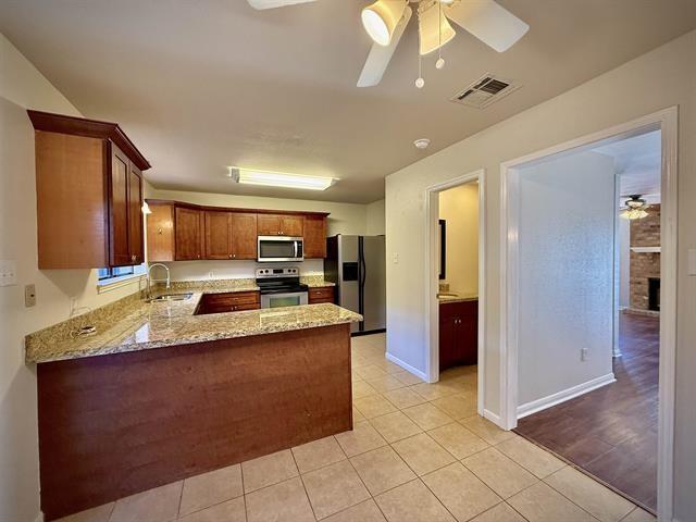 kitchen featuring ceiling fan, sink, kitchen peninsula, light tile patterned floors, and appliances with stainless steel finishes