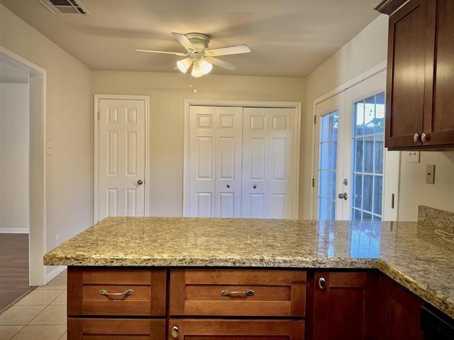 kitchen with ceiling fan, light stone countertops, light tile patterned floors, and french doors