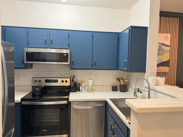 kitchen featuring backsplash, blue cabinets, kitchen peninsula, and appliances with stainless steel finishes