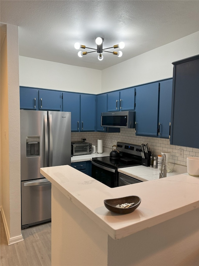 kitchen featuring blue cabinetry, backsplash, stainless steel appliances, and kitchen peninsula