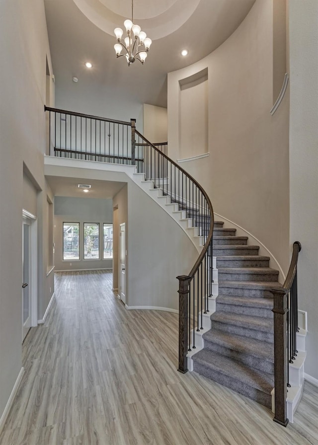 entryway featuring a towering ceiling, light hardwood / wood-style floors, and a notable chandelier