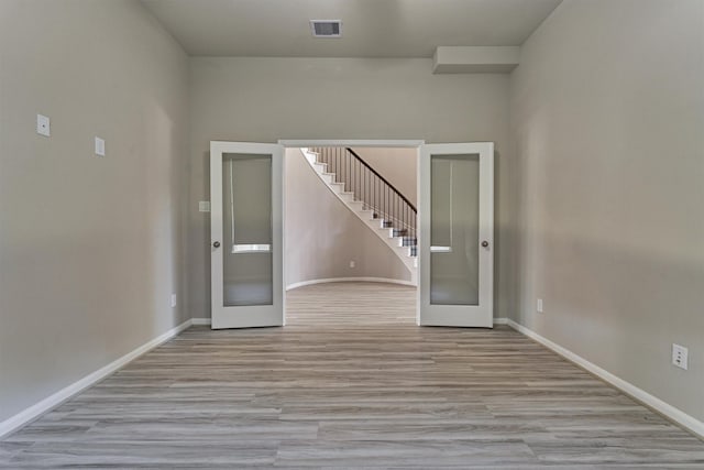 spare room with french doors and light hardwood / wood-style flooring