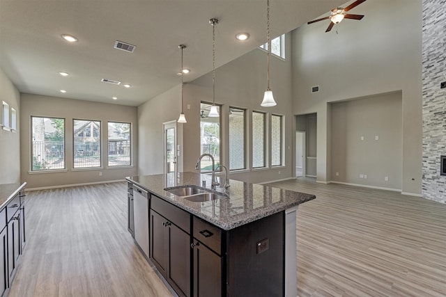 kitchen with light stone counters, sink, stainless steel dishwasher, and light hardwood / wood-style flooring